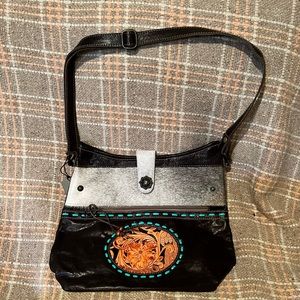 Black and grey hair on hide with leather tooling